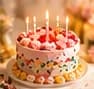 Birthday cake with lit candles and colourful sprinkles