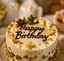 Cake decorated with a gold Happy Birthday message